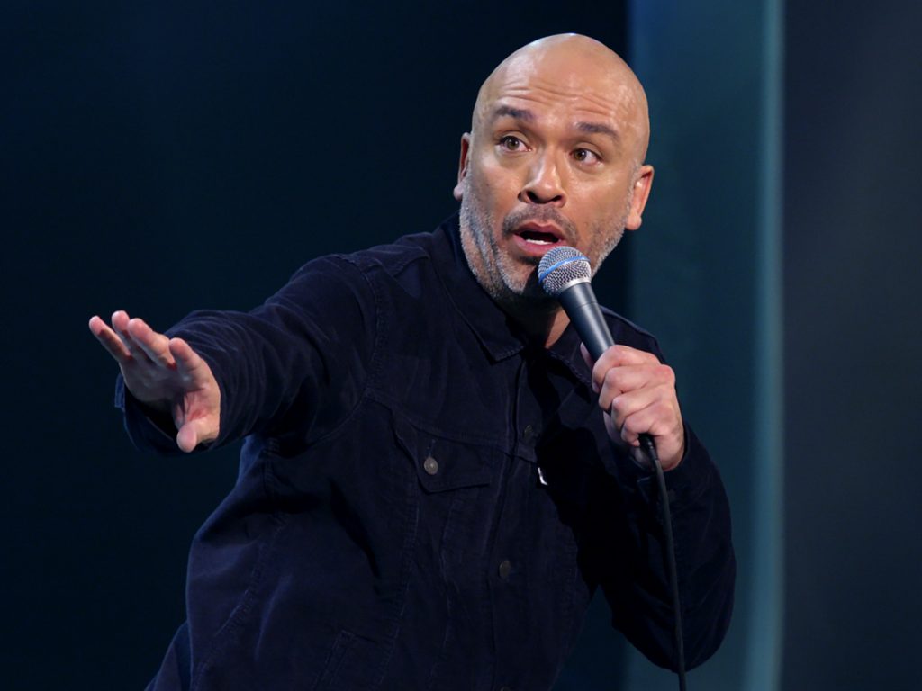 Jo Koy performing on stage holding a microphone