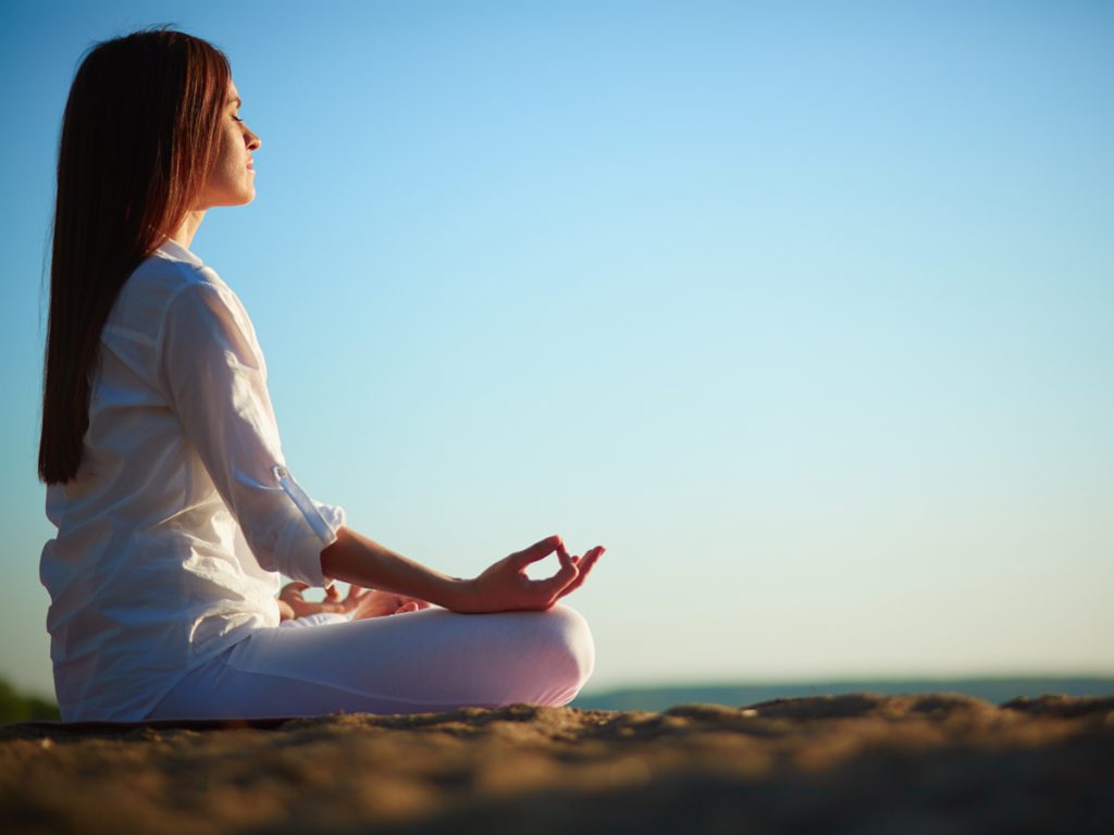 Courses that will change your life: woman sitting outside meditating and doing yoga