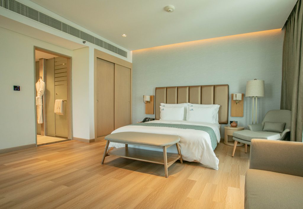 Zoya health and wellbeing resort: bedroom  with wooden floor and robe in bathroom