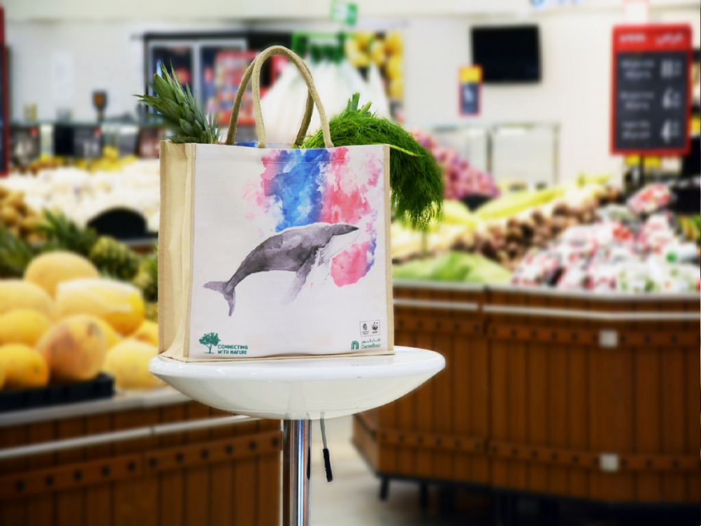 Carrefour replaces plastic bags: resusable cloth bag with a watercolour whale at Carrefour in front of fruit and vegetables